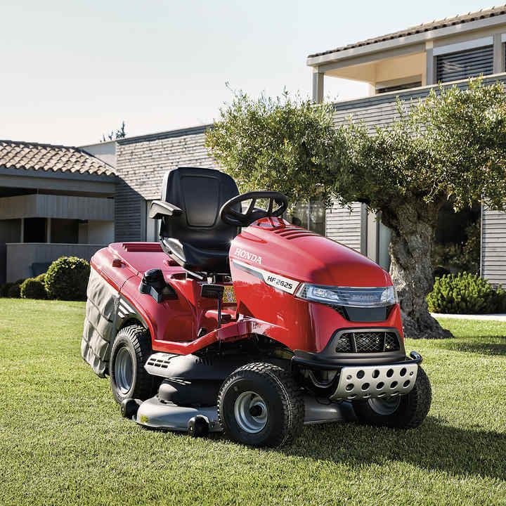 Vue de trois quarts face de la tondeuse Honda dans un jardin avec une maison en arrière-plan